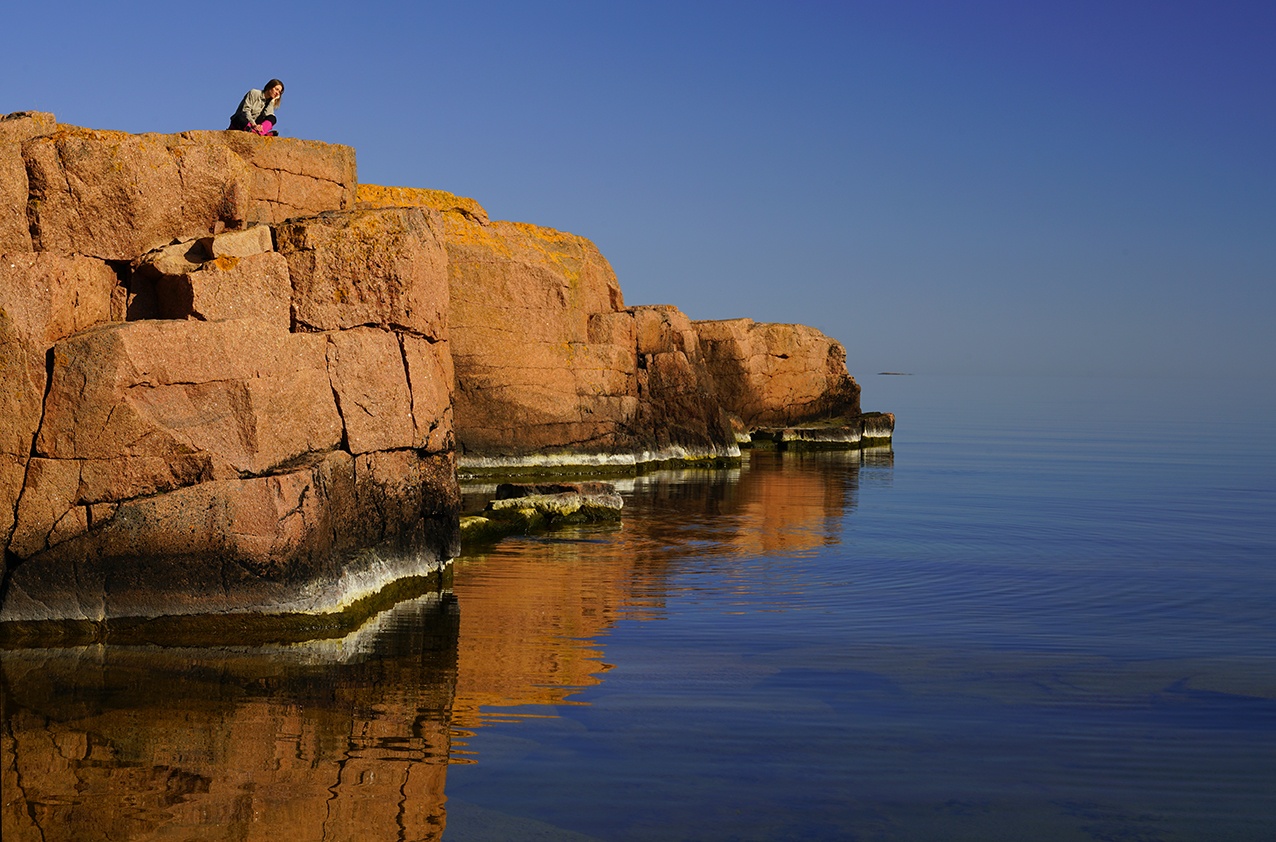 En person sitter på klippor vid vattnet, Fotograf: Andy Horner